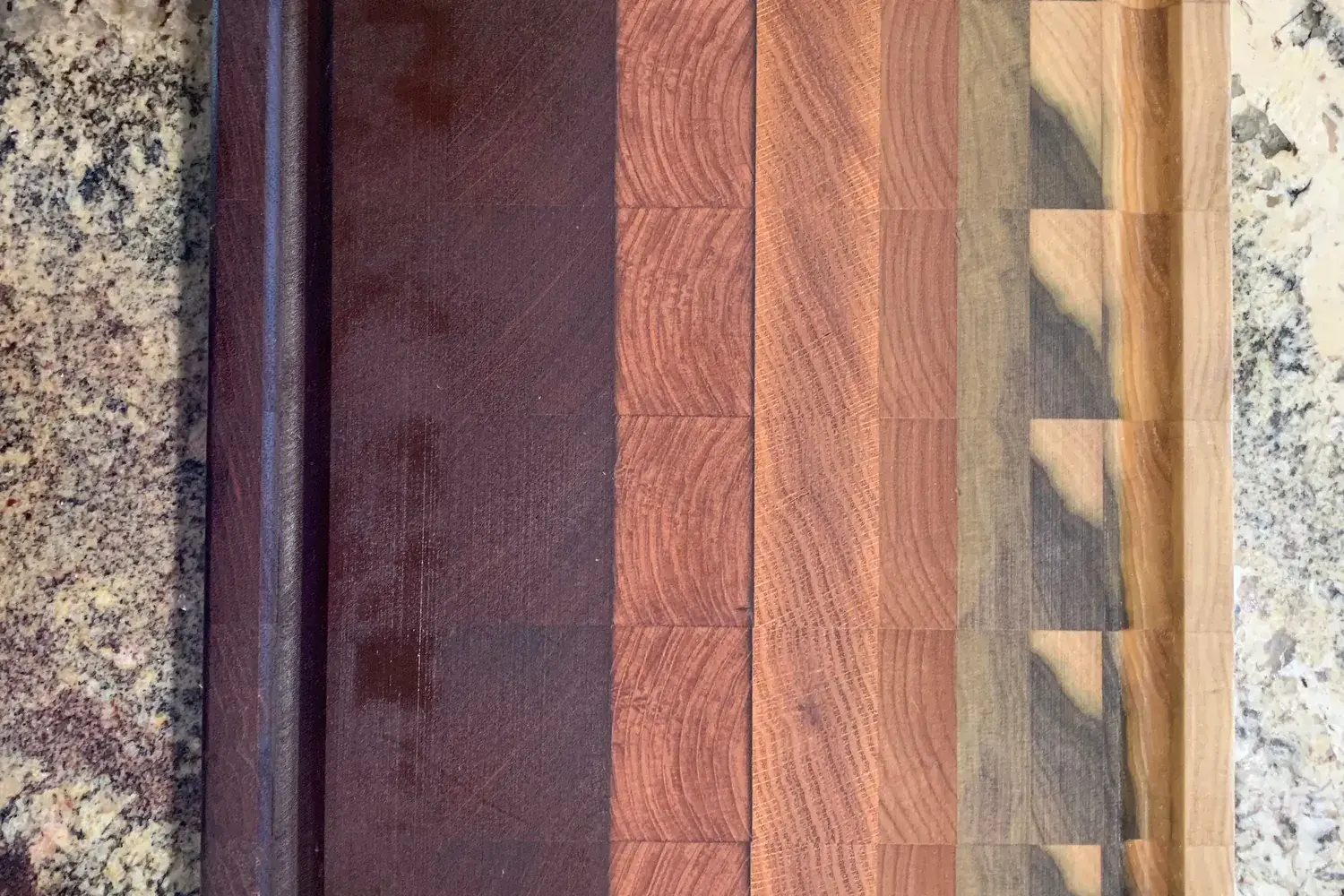 A striped hardwood cutting board made of alternating light and dark wood strips