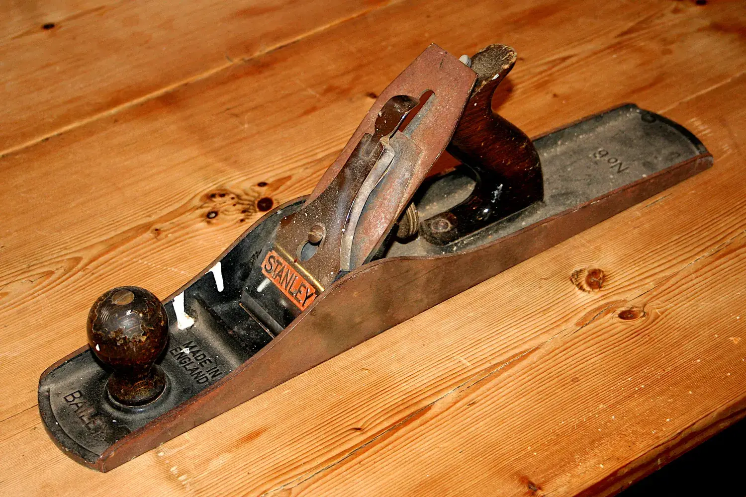 A vintage metal fore plane resting on a flat pine board