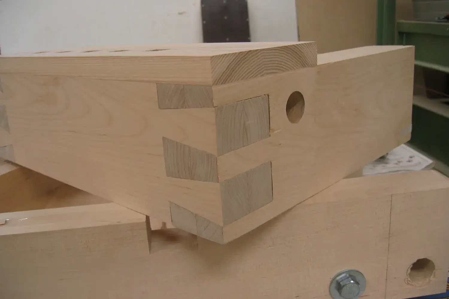 A close-up of a finished through-dovetail joint in light-colored birch