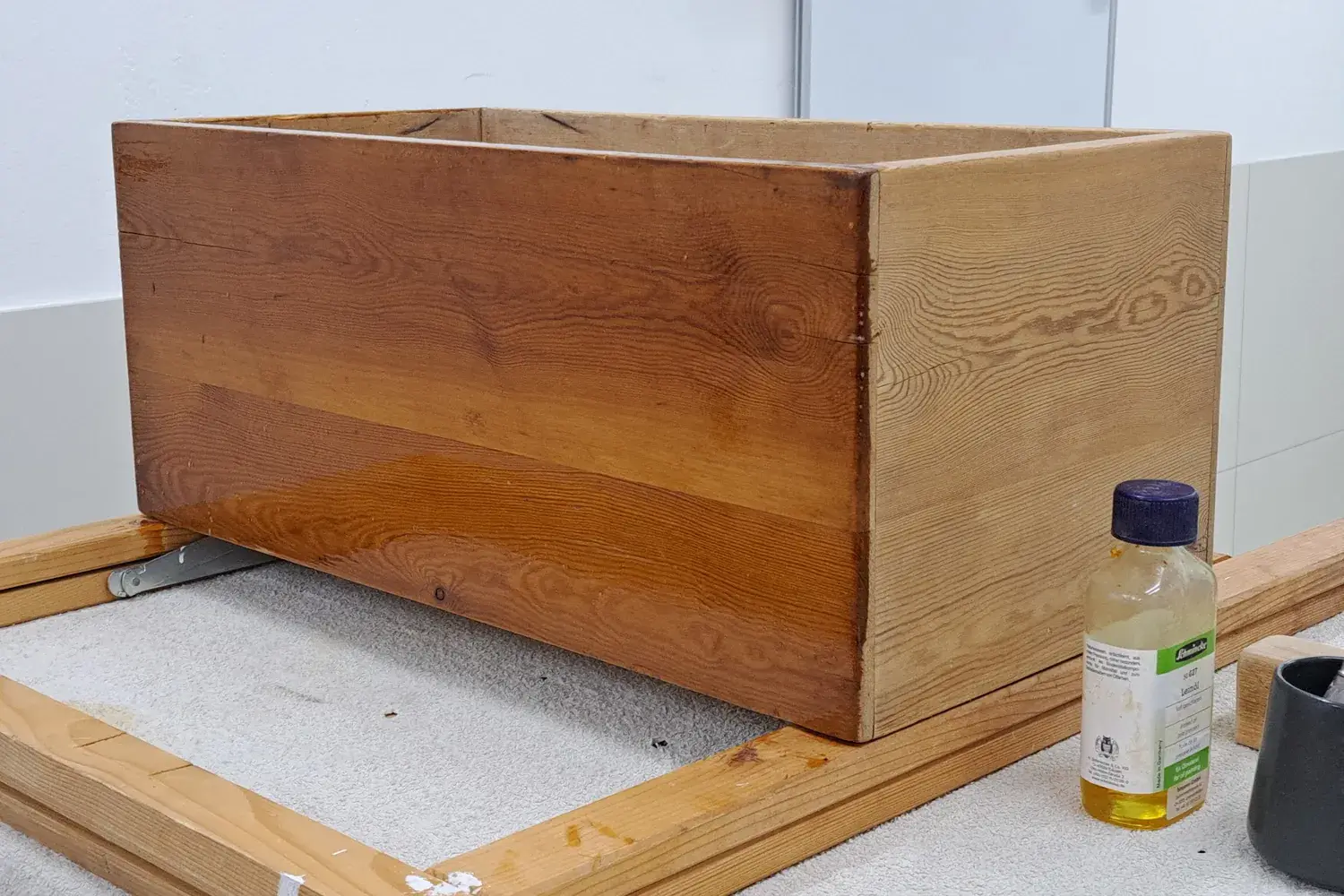 A simple pine box glistening with a fresh coat of linseed oil, next to a bottle of oil